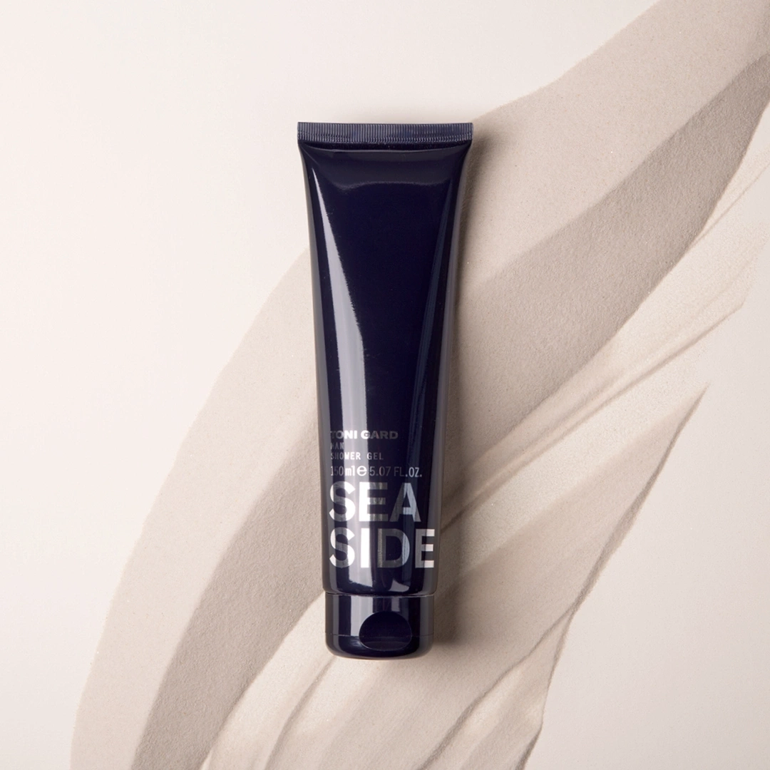 Dunkelblaue Tube mit Duschgel auf sandigem Untergrund, Seaside-Design.