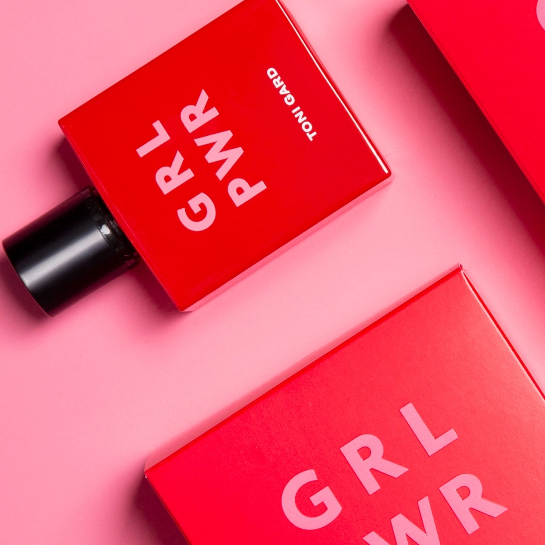 Rote Kosmetikprodukte mit GRL PWR-Schriftzug auf rosa Hintergrund.