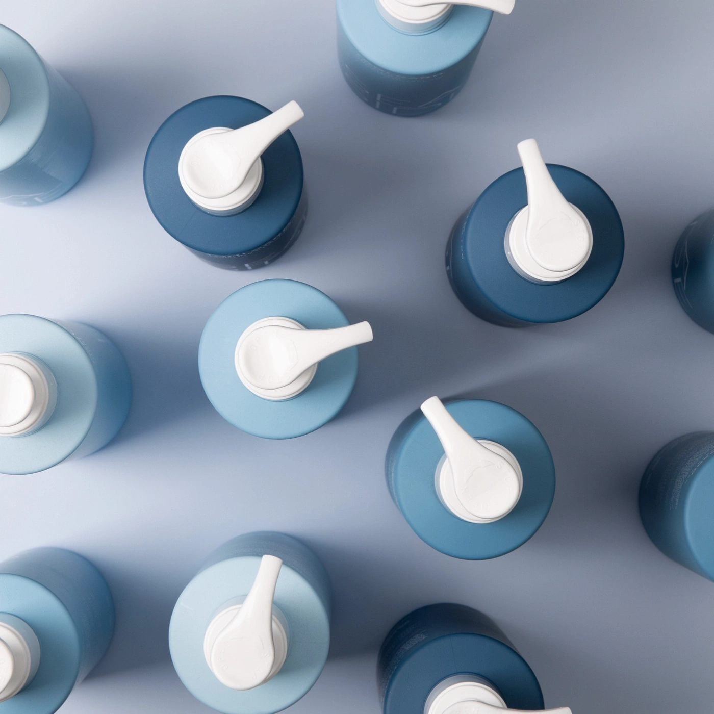 Overhead shot of blue bottles with white pumps on a blue background.