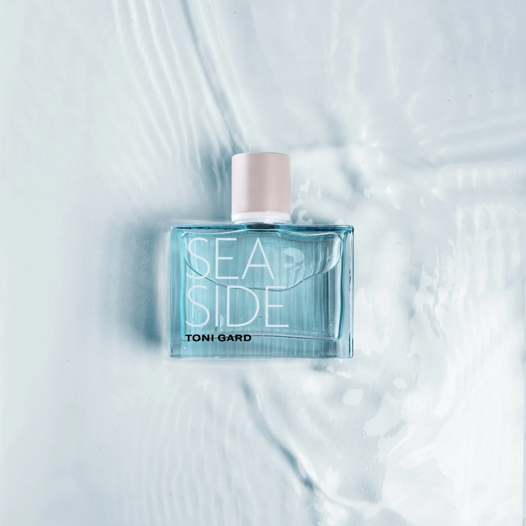 Parfümflasche mit der Aufschrift SEASIDE auf blauem Hintergrund mit Wasser.