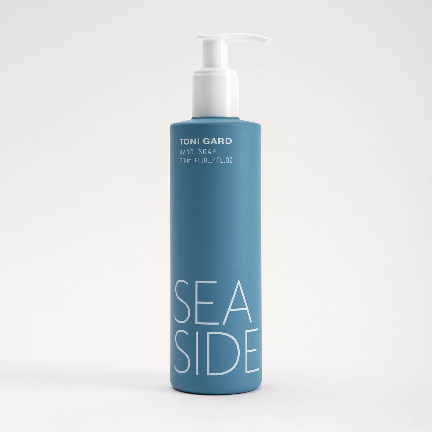 Blue hand soap bottle with white dispenser, reads 'SEA SIDE' and 'TONI GARD' on the label