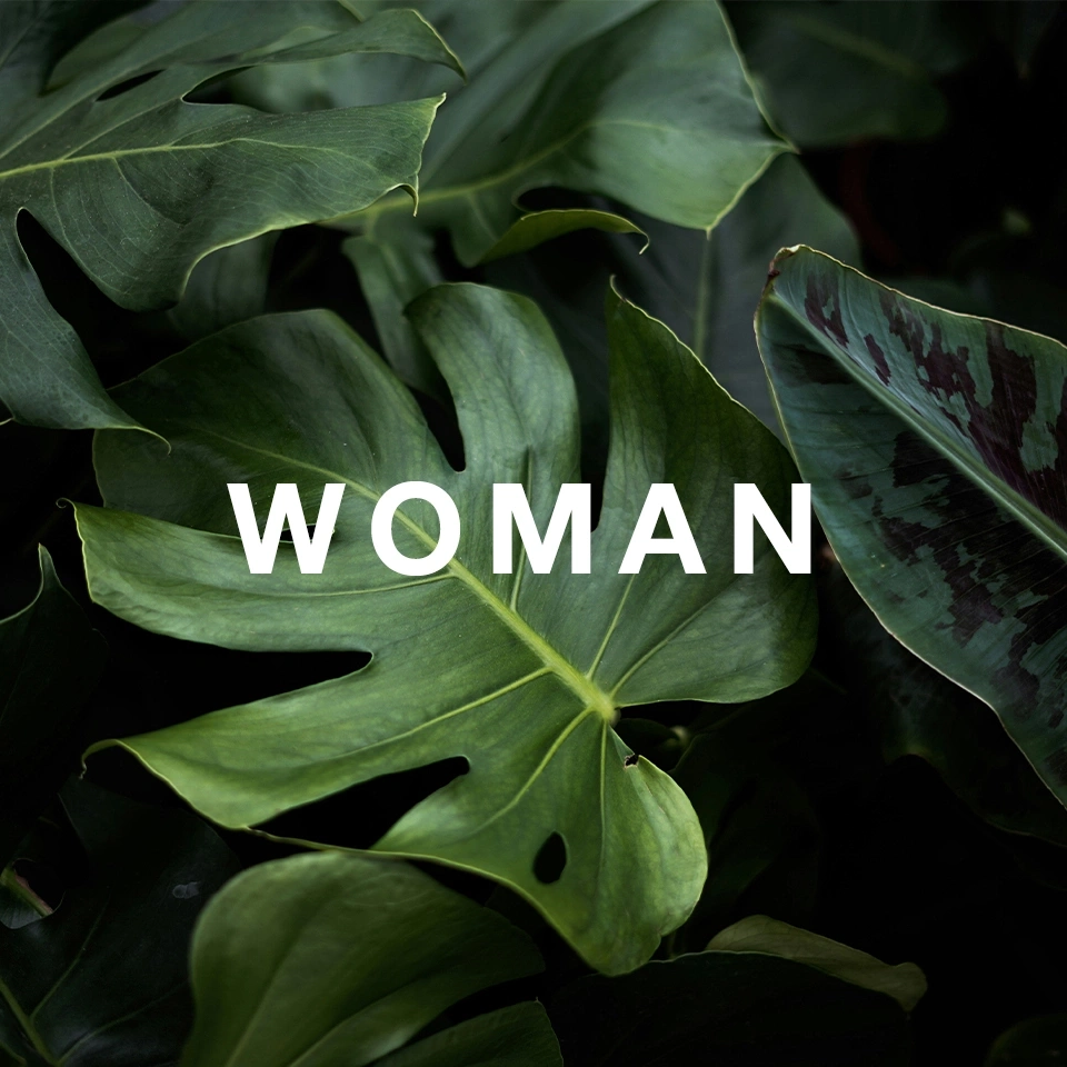 Grüne Blätter mit dem Wort 'WOMAN' in weißer Schrift.