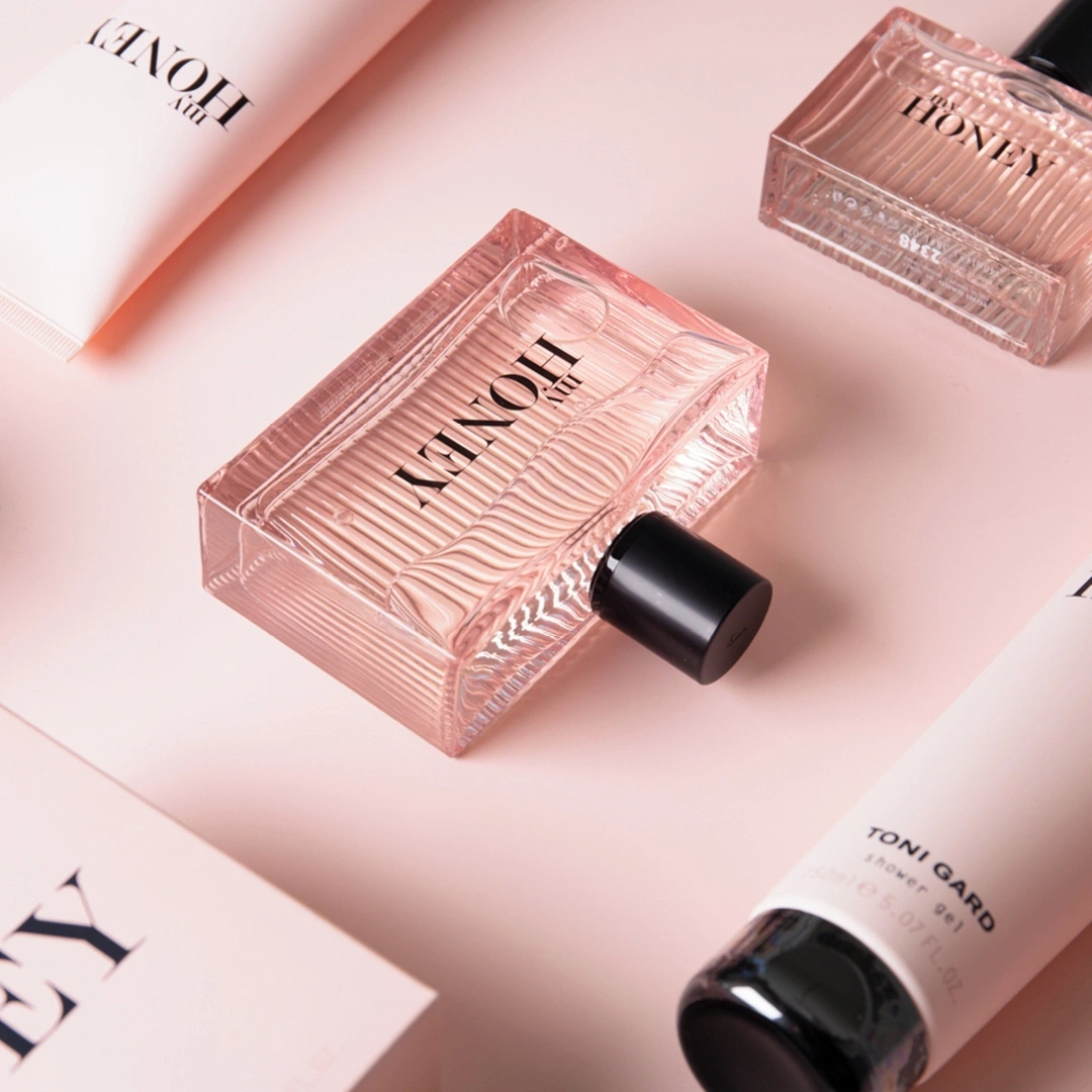 Pink cosmetics: perfume bottles, shower gel, and cream on a pink background.