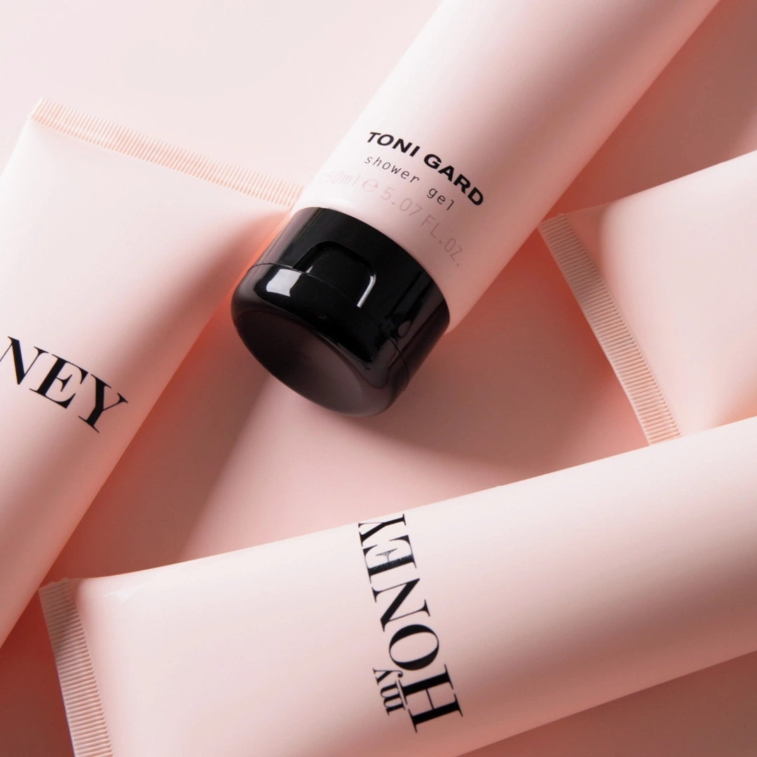 Pink shower gel tubes with 'Honey' and 'Toni Gard' on a pink background.