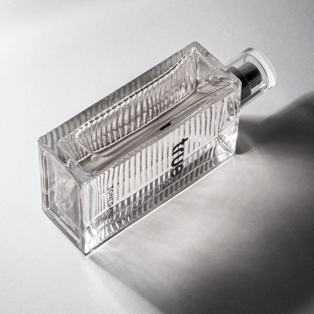 Parfümflasche aus Glas, rechteckig, mit schwarzem Verschluss, auf hellem Hintergrund
