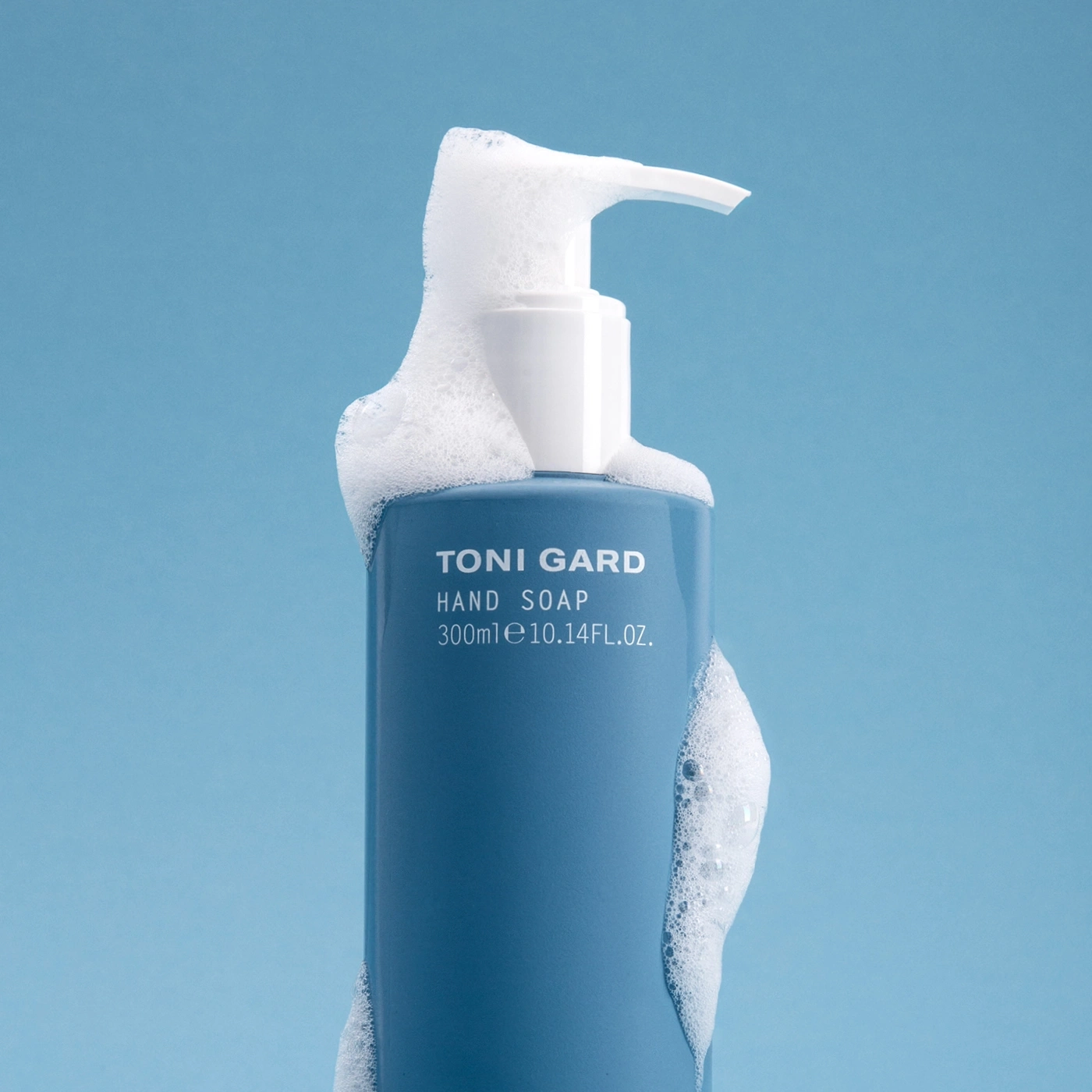 Blue hand soap bottle with foam, Toni Gard brand, 300ml, 10.14FL.OZ. on blue background
