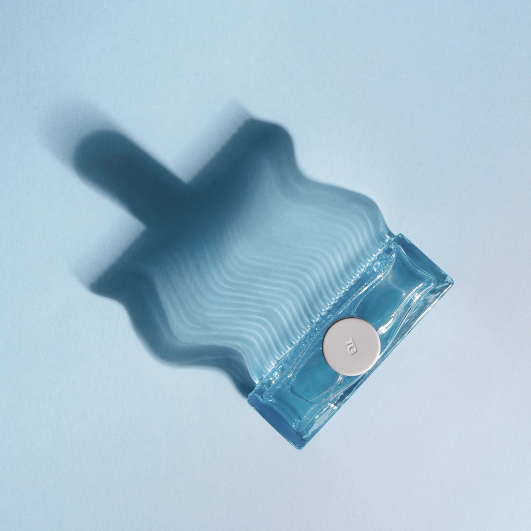 Blaues Parfüm mit Schatten auf blauem Hintergrund, minimalistisch