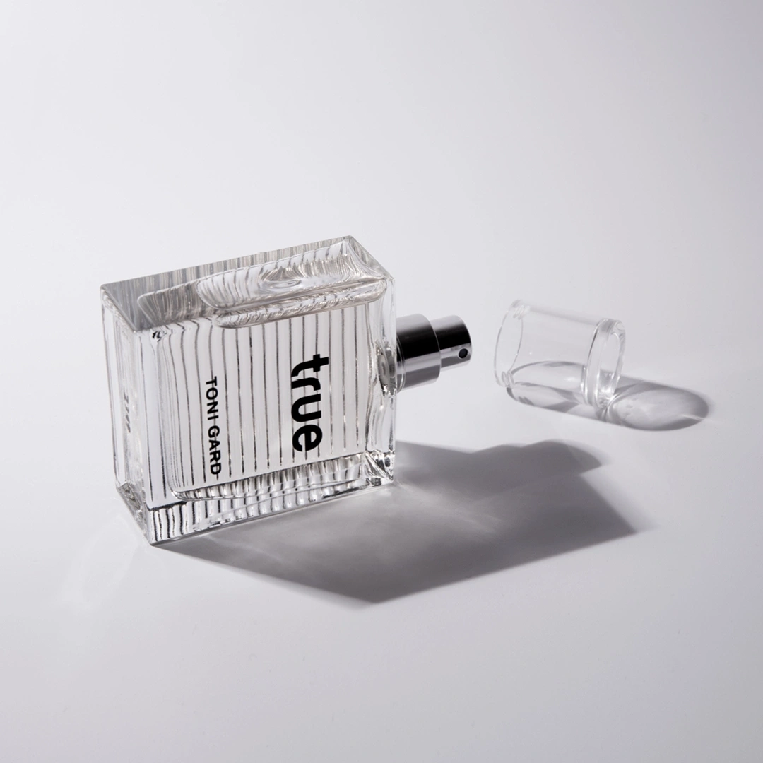 Perfume bottle with the word 'true' and 'TONI GARD' on it, with the cap off.