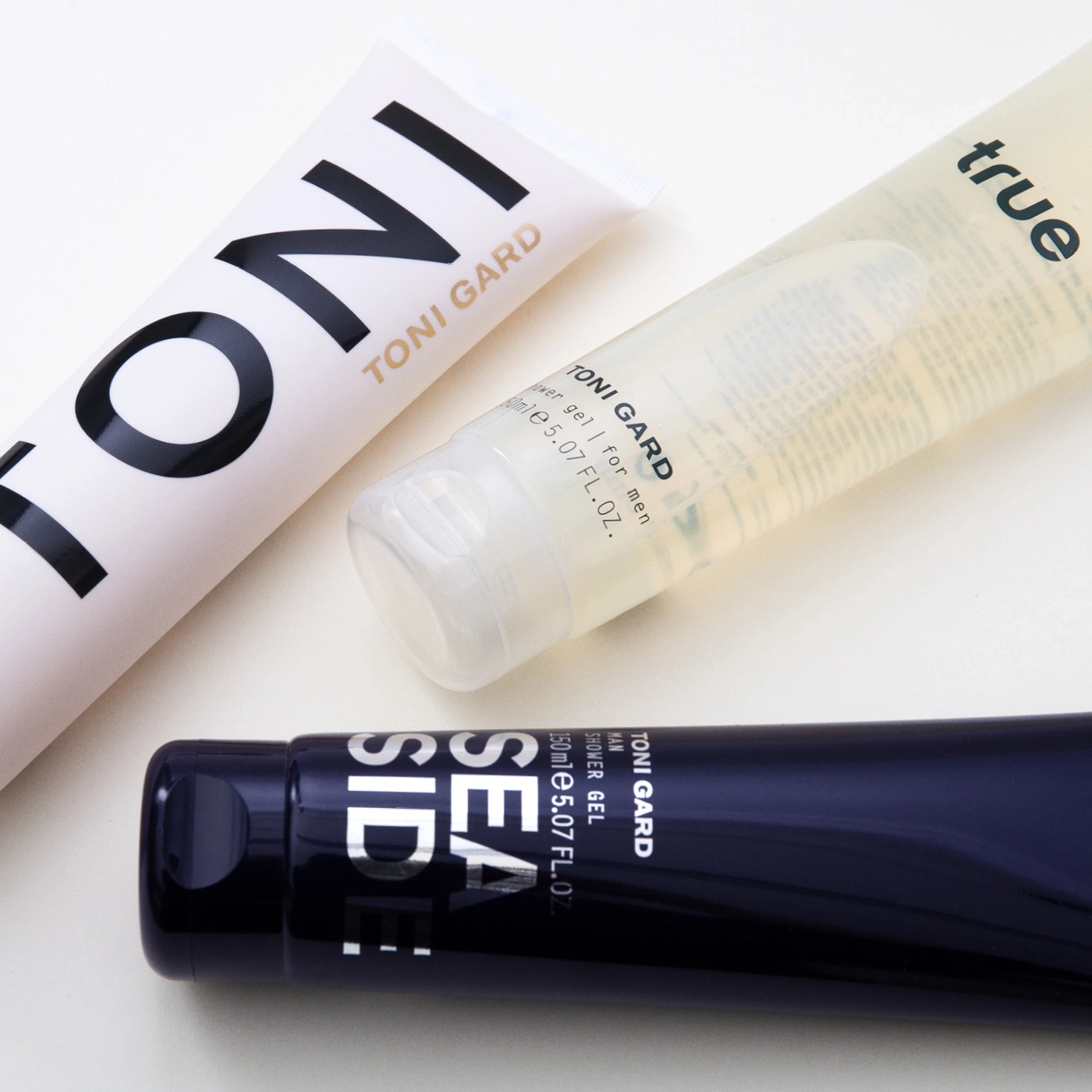 Drei Kosmetikprodukte von Toni Gard: Duschgel, Lotion, Creme, für Männer, auf hellem Hintergrund.