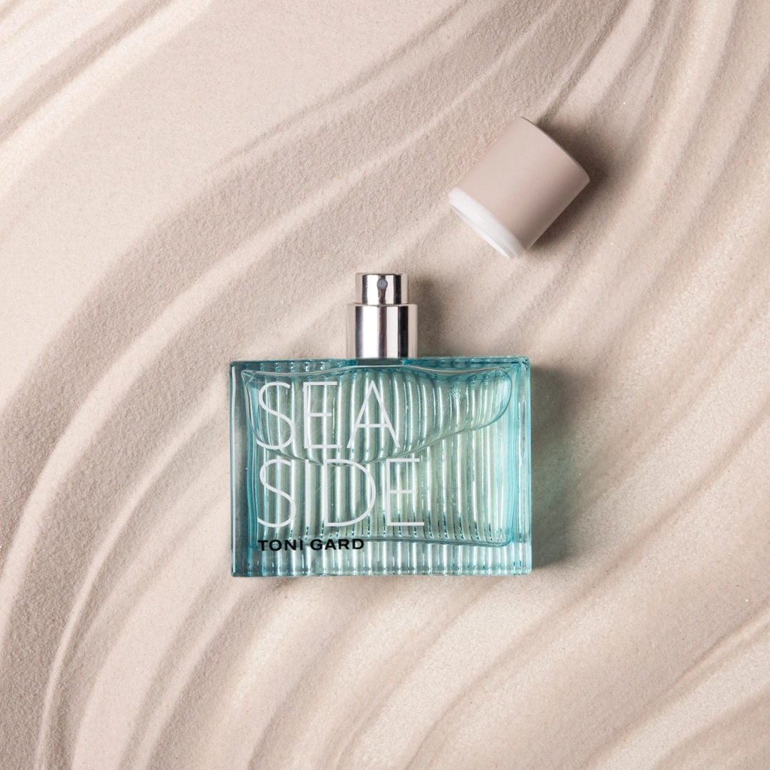 Parfümflasche mit der Aufschrift "SEASIDE" auf Sand, mit Deckel.