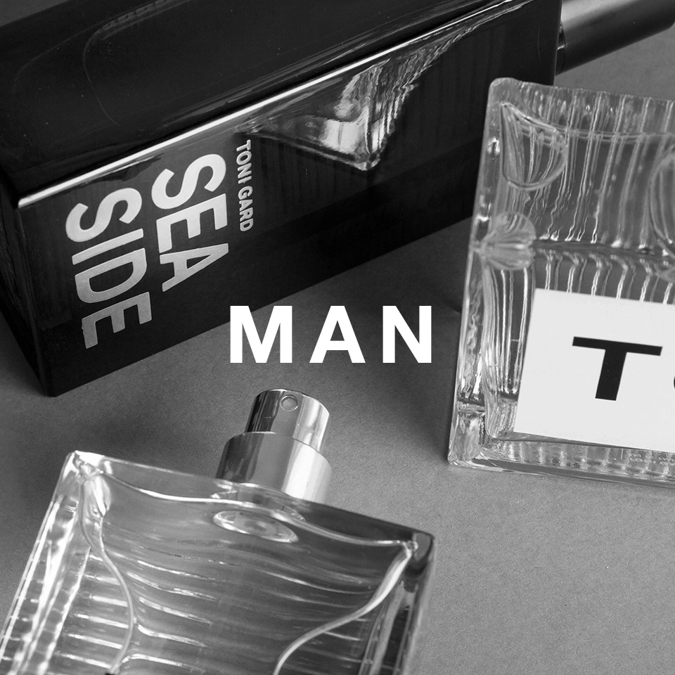 Schwarz-Weiß-Foto von Parfümflaschen mit dem Wort 'MAN' in Großbuchstaben.