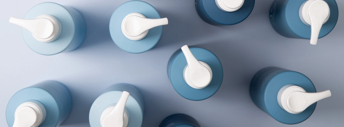 Blue bottles with white pumps on blue background, top view