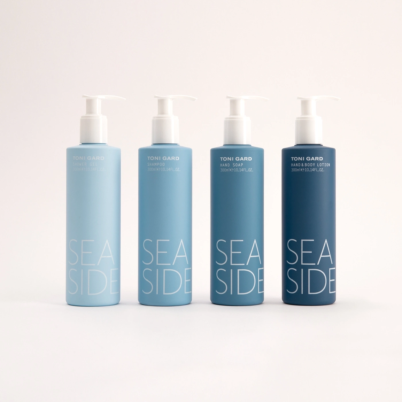 Four blue bottles with white text, 'SEA SIDE' and 'TONI GARD' branding.